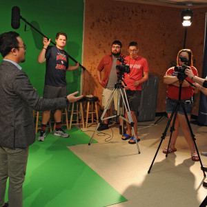 students with green screen and camera