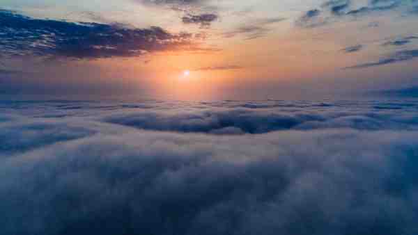 above the clouds with sunset in distance